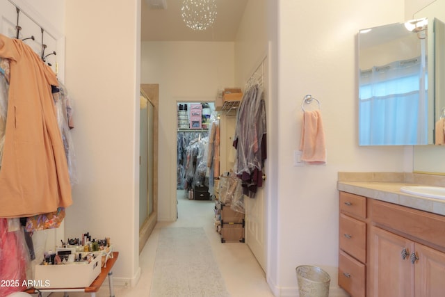 full bath with a stall shower, a walk in closet, a chandelier, and vanity