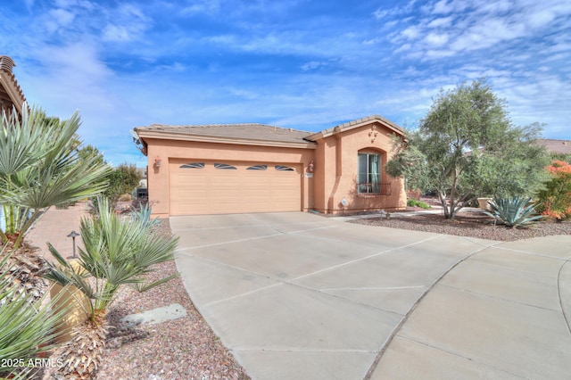 mediterranean / spanish home with a tile roof, driveway, an attached garage, and stucco siding