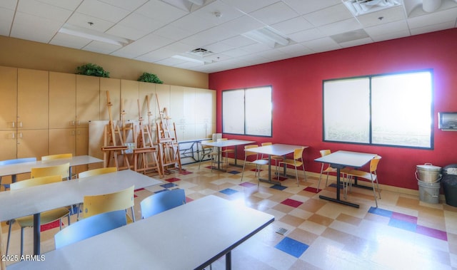 interior space with light floors, baseboards, visible vents, and a drop ceiling