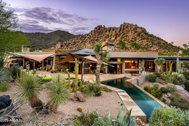 back house at dusk with a patio area and a mountain view