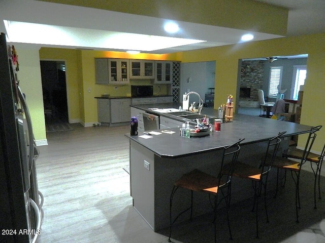 kitchen featuring ceiling fan, a large island with sink, a kitchen breakfast bar, and stainless steel appliances