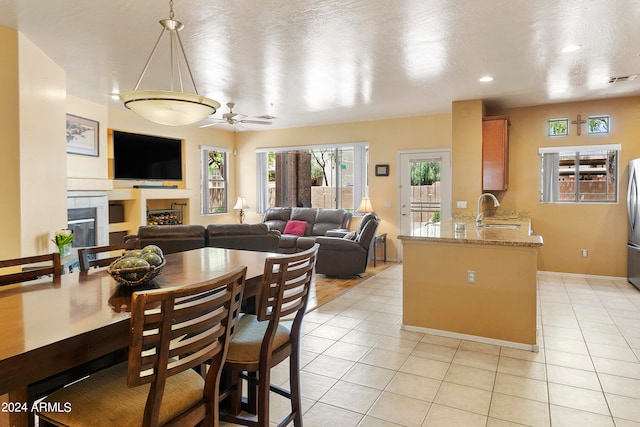 dining space with ceiling fan, light tile patterned floors, a textured ceiling, and sink