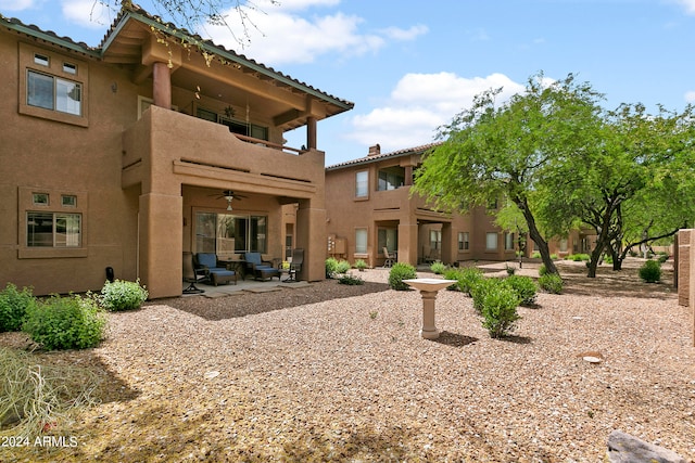 rear view of property featuring a balcony, ceiling fan, an outdoor living space, and a patio area