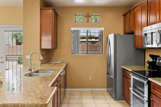 kitchen featuring light stone countertops, a wealth of natural light, stainless steel appliances, and sink