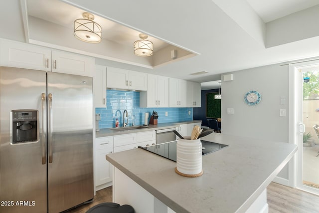 kitchen featuring appliances with stainless steel finishes, a sink, white cabinets, and backsplash