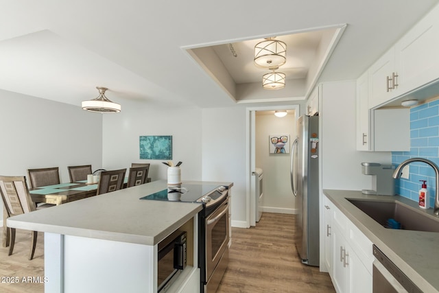 kitchen featuring appliances with stainless steel finishes, independent washer and dryer, a sink, a kitchen island, and tasteful backsplash