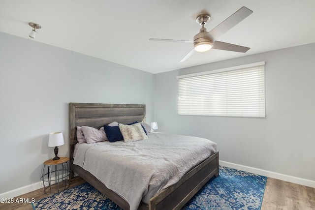 bedroom with baseboards, wood finished floors, and a ceiling fan