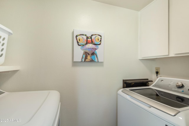clothes washing area featuring cabinet space and washer and clothes dryer