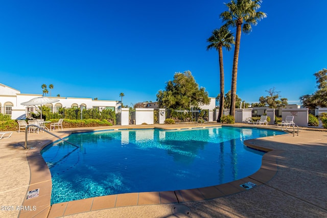 community pool with fence and a patio area