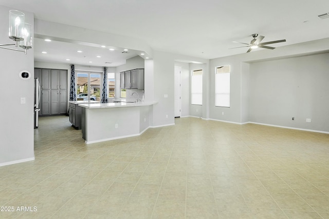 kitchen with sink, gray cabinets, stainless steel refrigerator, ceiling fan, and kitchen peninsula