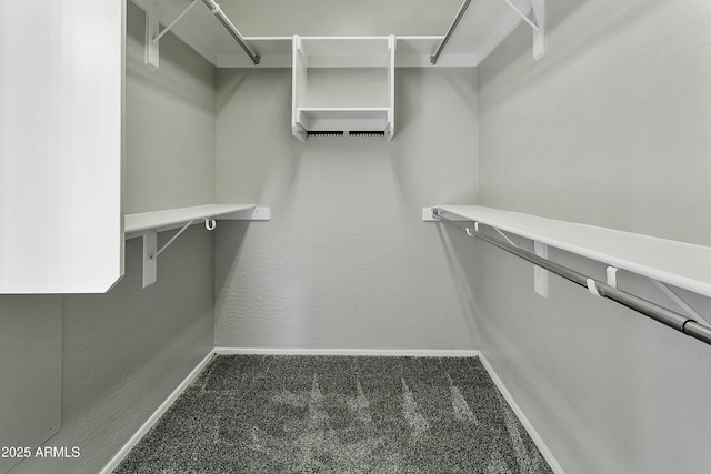 walk in closet with dark carpet