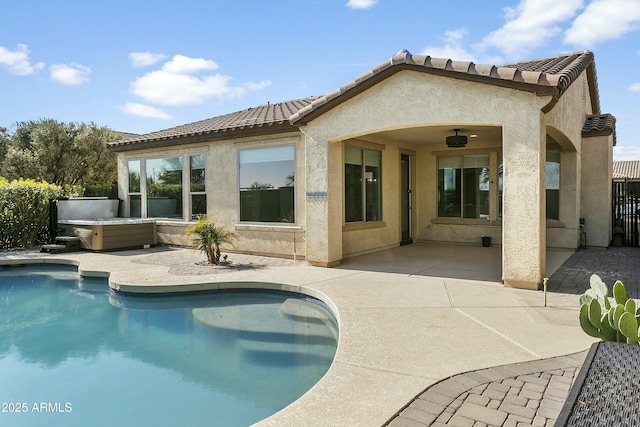 rear view of property with a pool with hot tub and a patio area