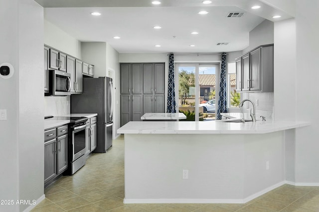 kitchen featuring stainless steel appliances, sink, gray cabinetry, and kitchen peninsula