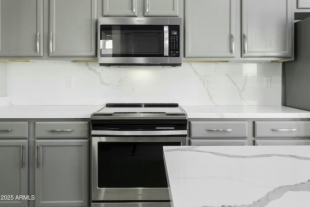 kitchen featuring gray cabinetry, light stone counters, tasteful backsplash, and stainless steel appliances