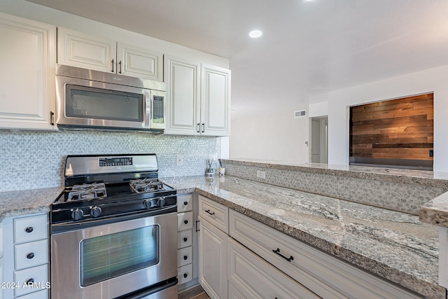 kitchen featuring light stone countertops, white cabinetry, stainless steel appliances, and backsplash