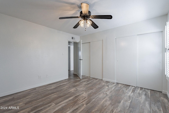 unfurnished bedroom with hardwood / wood-style flooring, ceiling fan, and two closets