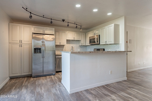 kitchen featuring white cabinets, tasteful backsplash, track lighting, stainless steel appliances, and light hardwood / wood-style floors