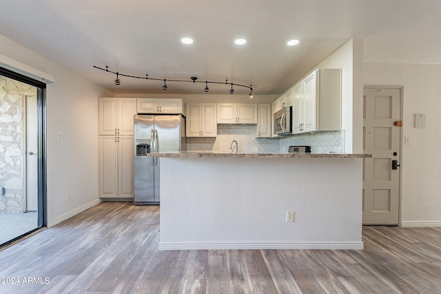 kitchen featuring light hardwood / wood-style floors, light stone countertops, stainless steel appliances, and white cabinets