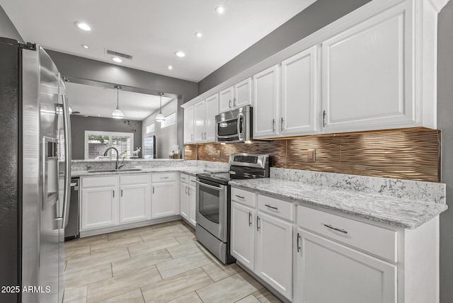 kitchen featuring a sink, appliances with stainless steel finishes, white cabinets, and pendant lighting