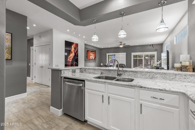 kitchen with decorative light fixtures, light stone counters, stainless steel dishwasher, white cabinetry, and a sink