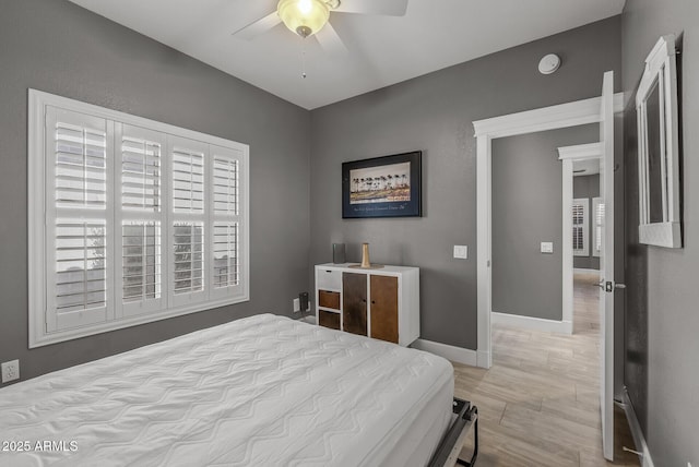 bedroom featuring ceiling fan, light wood-style floors, and baseboards