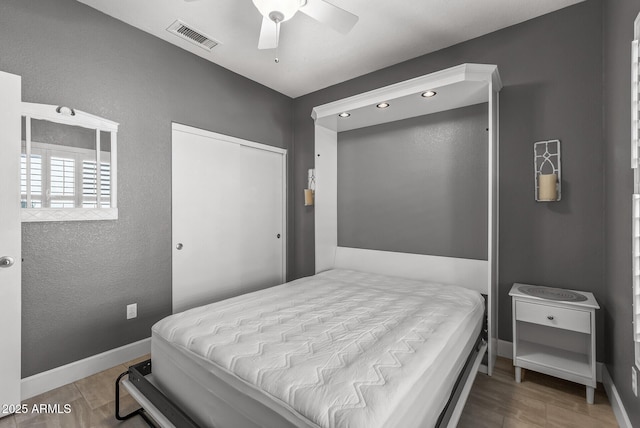 bedroom featuring visible vents, baseboards, a closet, and wood finished floors