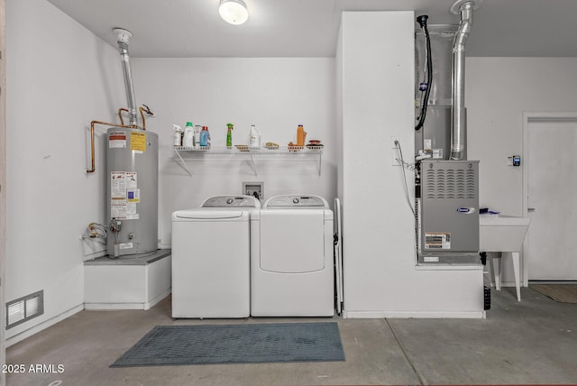 clothes washing area featuring visible vents, baseboards, laundry area, water heater, and washer and dryer