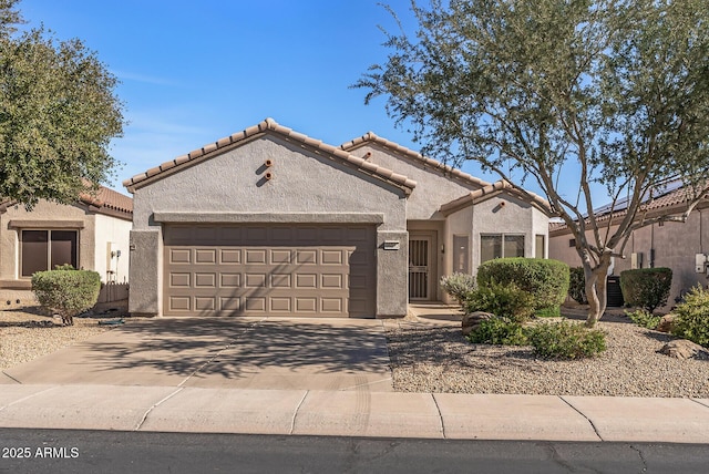 mediterranean / spanish-style house with concrete driveway, a tiled roof, an attached garage, and stucco siding