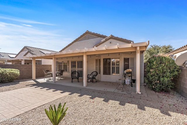 back of property with stucco siding, a patio, a tile roof, and fence