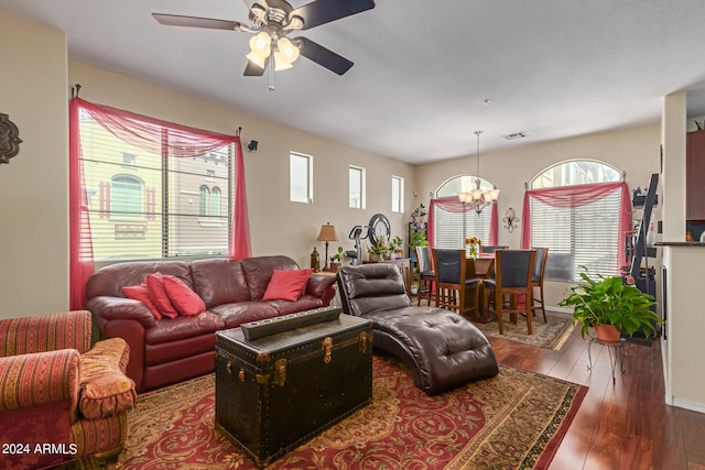 living room with ceiling fan with notable chandelier and dark hardwood / wood-style flooring