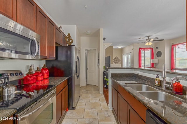 kitchen with stainless steel appliances, dark stone countertops, ceiling fan, and sink