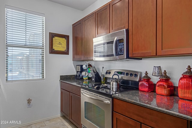 kitchen featuring dark stone counters, appliances with stainless steel finishes, and light tile patterned floors