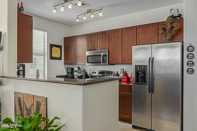 kitchen featuring kitchen peninsula, dark stone countertops, sink, and stainless steel appliances