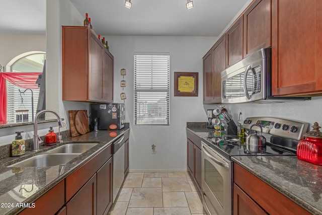 kitchen with dark stone counters, stainless steel appliances, and sink