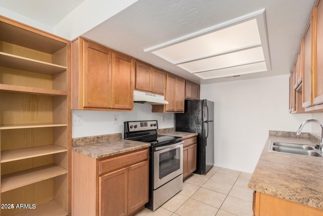 kitchen featuring a sink, stainless steel range with electric cooktop, under cabinet range hood, light tile patterned floors, and freestanding refrigerator