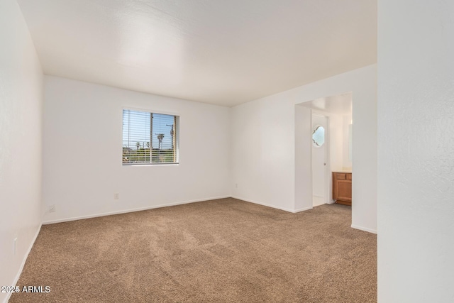 carpeted empty room featuring baseboards