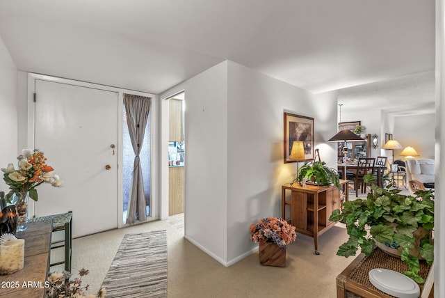 entryway with baseboards and light colored carpet
