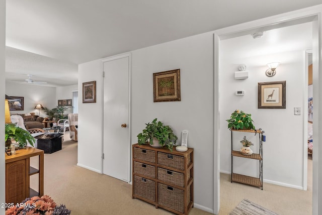 hall featuring baseboards and light colored carpet