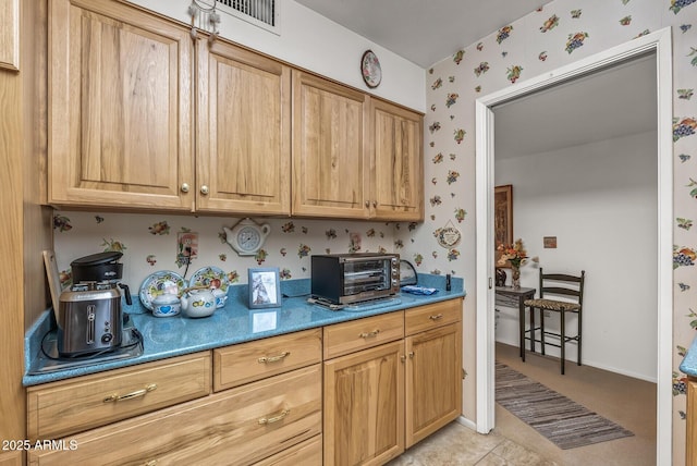 kitchen featuring light countertops, a toaster, baseboards, and wallpapered walls
