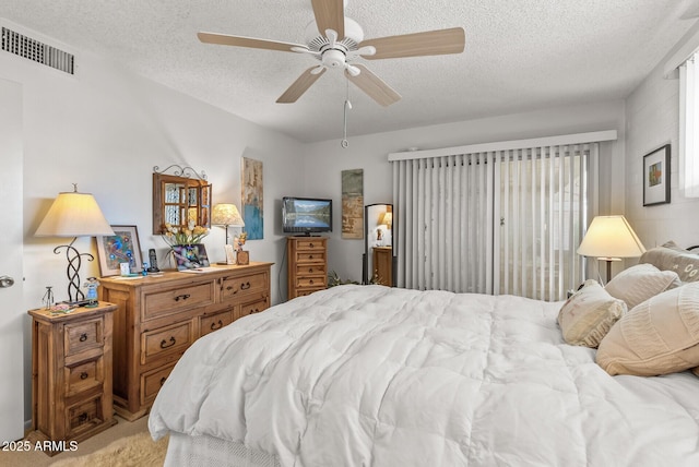 carpeted bedroom featuring a textured ceiling, ceiling fan, and visible vents