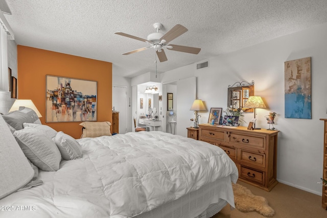 bedroom with a textured ceiling, carpet flooring, visible vents, and a ceiling fan