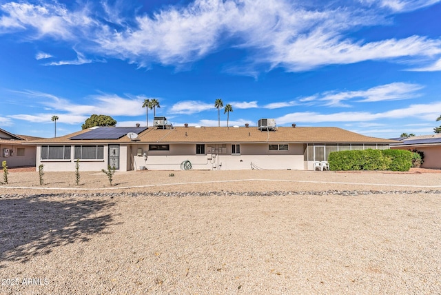 view of front of property with central AC unit, solar panels, and stucco siding