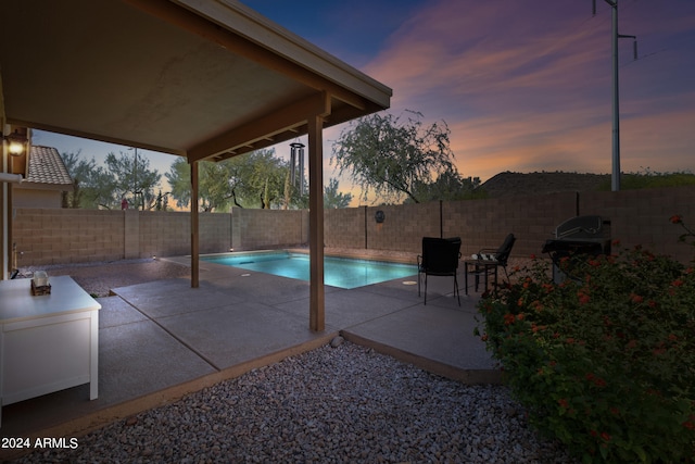 pool at dusk featuring a patio area