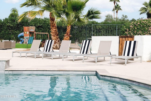 view of swimming pool featuring playground community, a patio, fence, and a fenced in pool