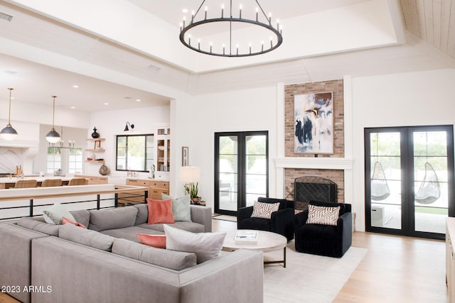 living room featuring french doors, a fireplace, light wood-style flooring, and a high ceiling