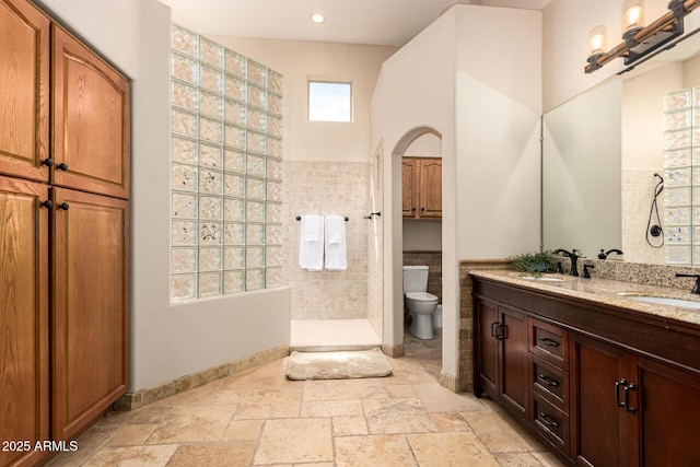 bathroom featuring a walk in shower, stone tile floors, a sink, and toilet