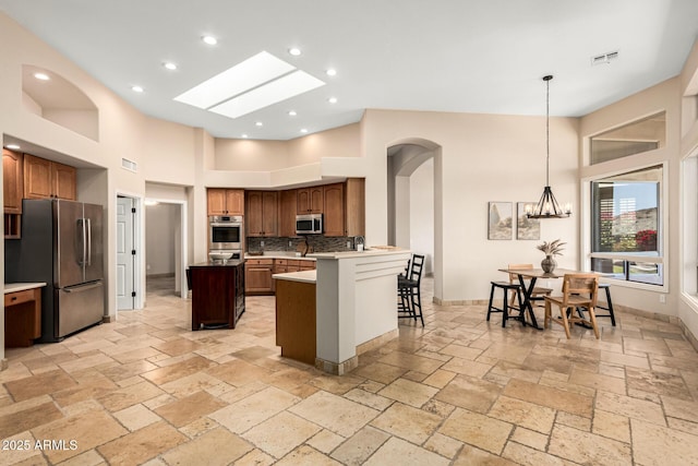 kitchen featuring arched walkways, a kitchen island, stone tile floors, and stainless steel appliances