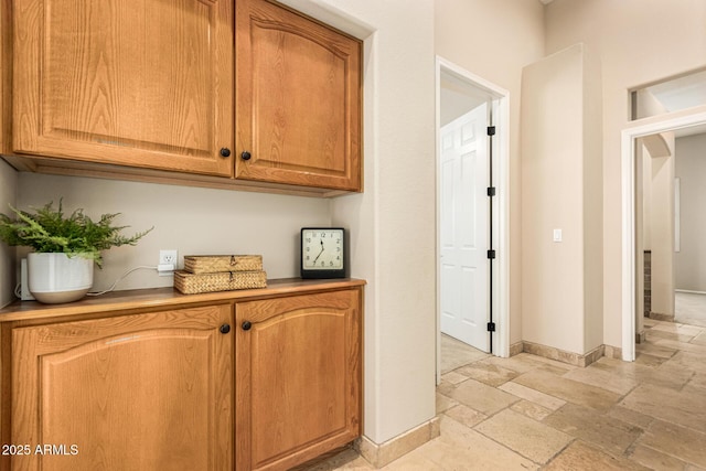 corridor with baseboards and stone tile floors