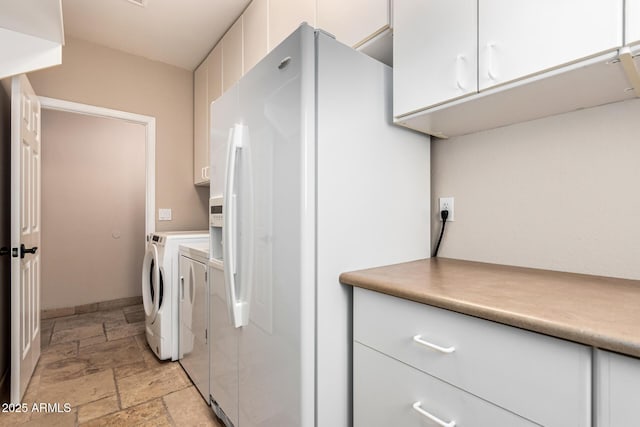 clothes washing area with stone tile floors, cabinet space, and washing machine and dryer