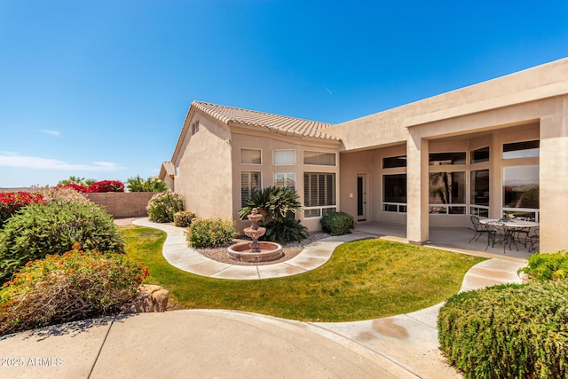 rear view of property with a yard, a patio area, stucco siding, and fence